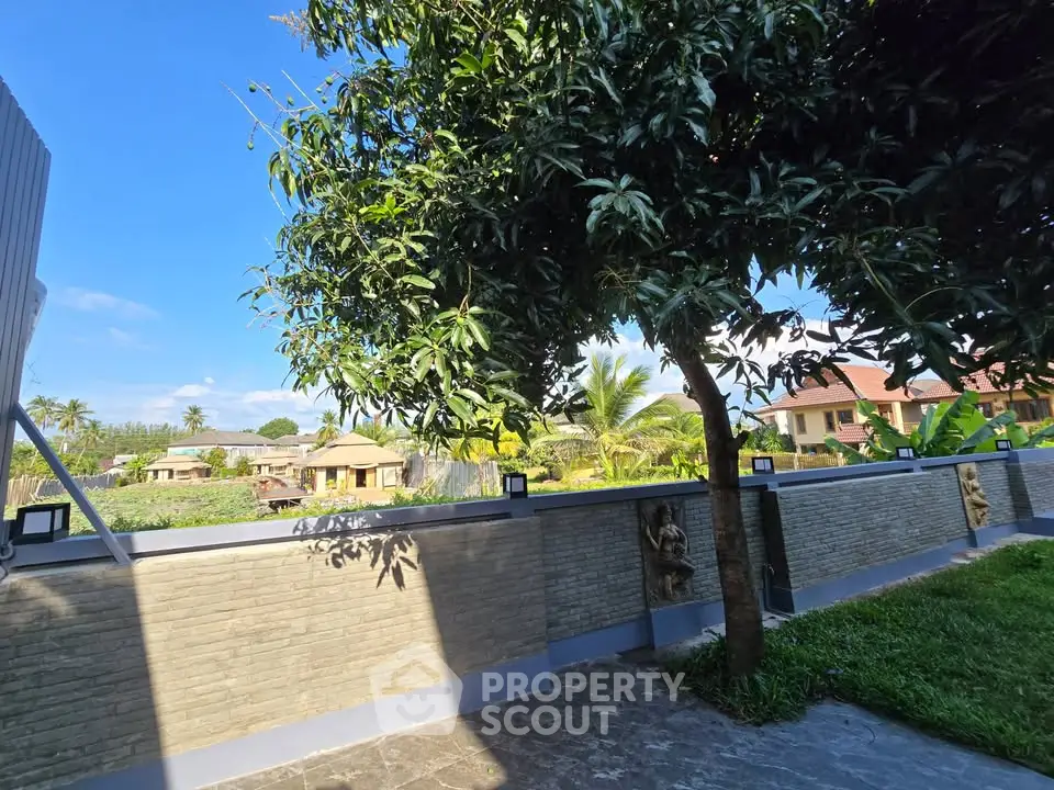 Charming garden view with lush greenery and modern stone wall in serene residential area.