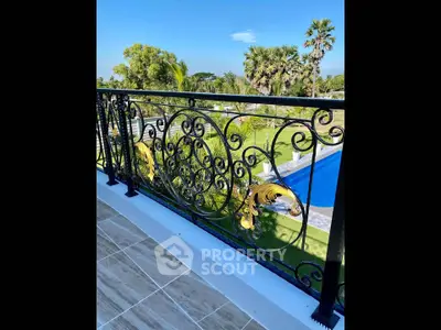 Luxurious balcony with ornate railing overlooking lush garden and pool