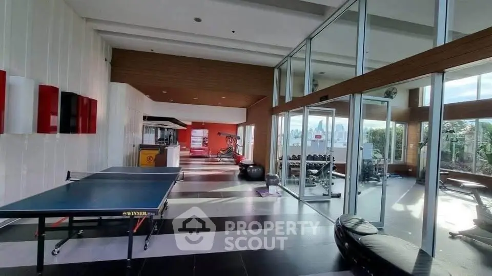 Spacious gym with modern equipment and glass walls offering a scenic view, perfect for fitness enthusiasts.