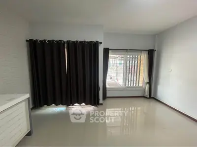 Spacious unfurnished room with large windows and dark curtains, perfect for customization.
