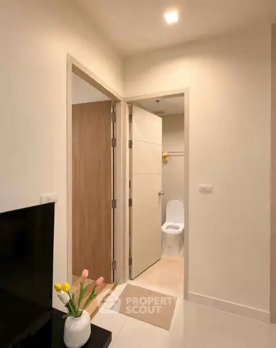 Modern apartment interior with hallway leading to bathroom, featuring sleek design and neutral tones.