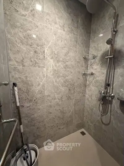Modern bathroom with sleek marble tiles and contemporary shower fixtures.