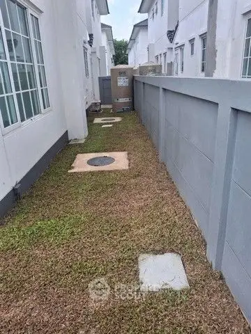 Narrow side yard with grass and utility access in modern residential area.