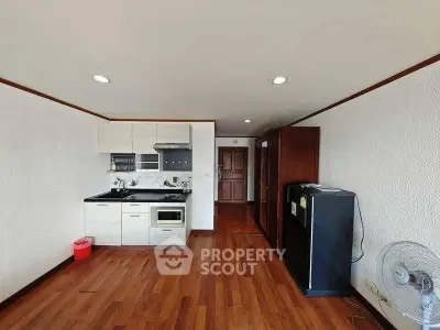 Spacious kitchen with wooden flooring and modern appliances in a cozy apartment.