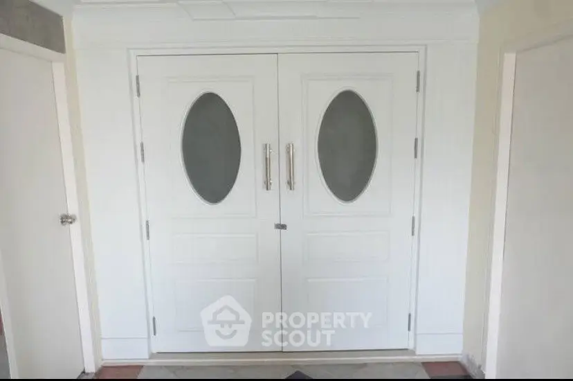 Elegant white double doors with oval glass panels in a modern entranceway.