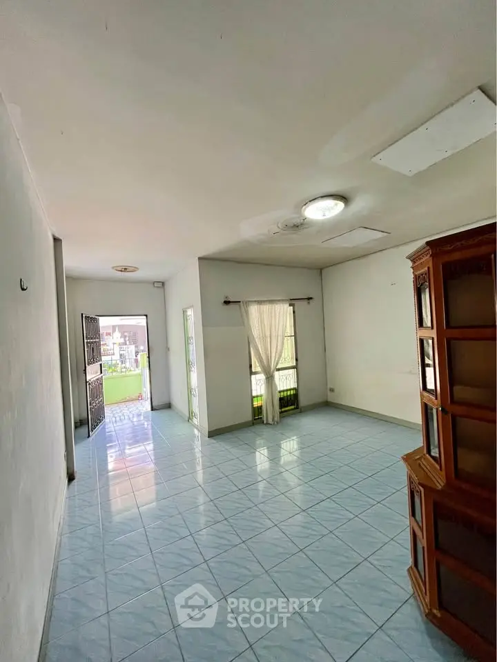 Spacious living room with tiled floor and natural light, ideal for family gatherings.