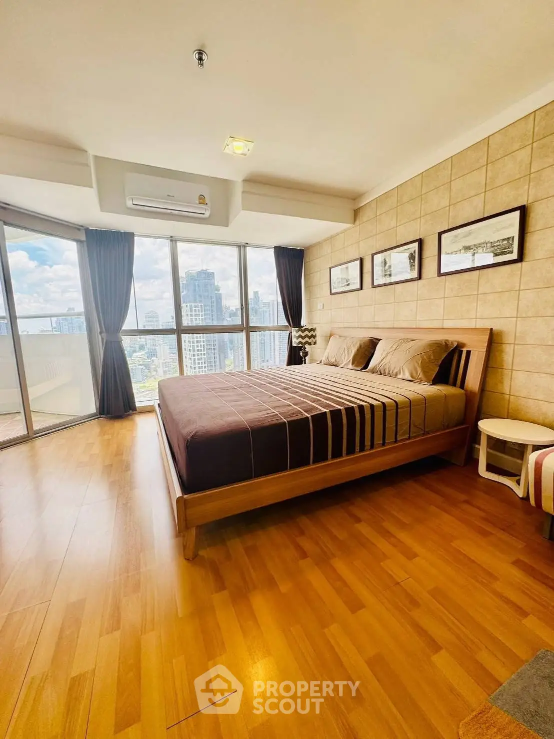 Spacious bedroom with panoramic city views and elegant wooden flooring