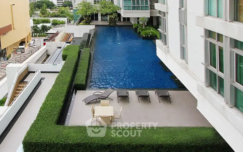 Luxurious apartment complex with stunning pool and relaxation area.