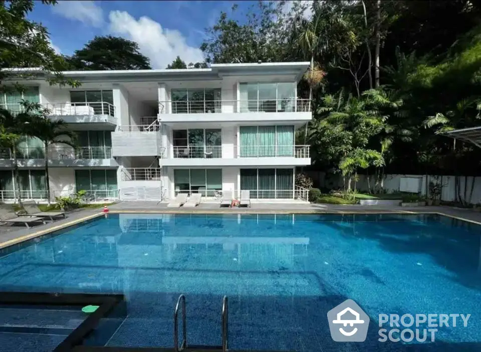 Luxurious apartment complex with a stunning pool and lush greenery.