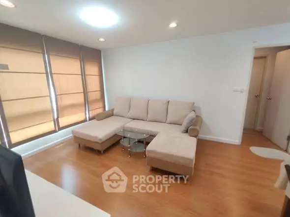 Spacious living room with modern beige sectional sofa and wooden flooring