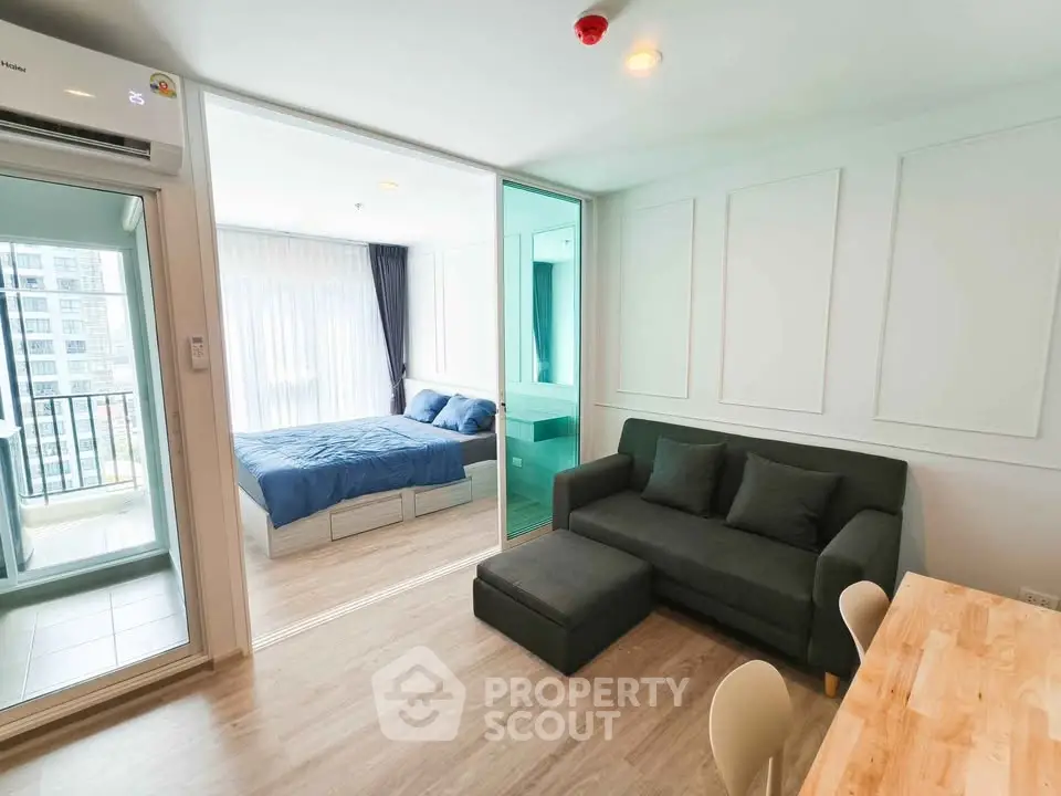 Modern studio apartment with open living area and cozy bedroom, featuring a balcony with city views.