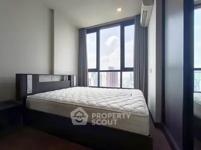 Spacious bedroom with large windows offering stunning city views, featuring a comfortable bed and modern design.