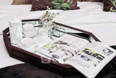 Elegant bedroom setting with a stylish tray featuring tea set and magazine, enhancing the cozy ambiance.