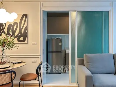 Modern living room with stylish decor and sliding door leading to a compact kitchen.