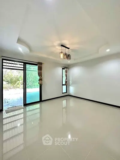 Spacious empty room with pool view and elegant ceiling light fixture