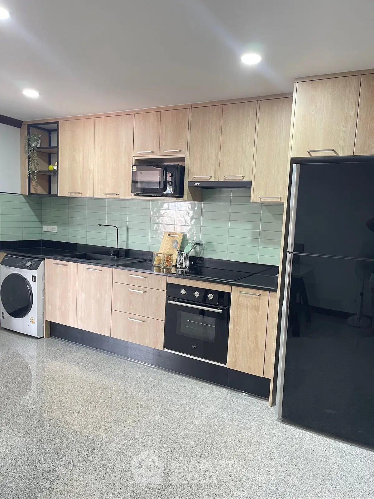 Modern kitchen with sleek appliances and stylish cabinetry, featuring a washing machine and built-in oven.