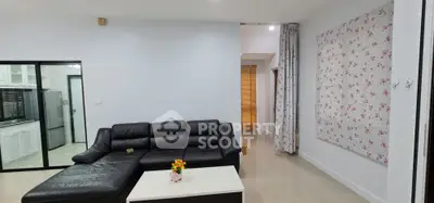 Spacious living room with modern black leather sofa and floral decor