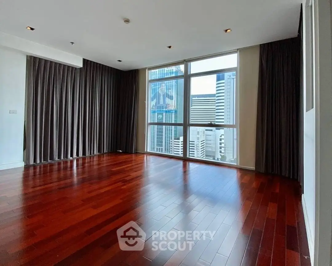 Spacious empty living room with hardwood floors and city view