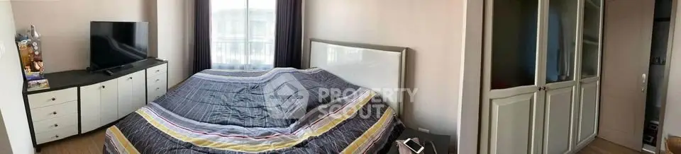 Spacious bedroom with modern decor and ample storage space, featuring a large window for natural light.