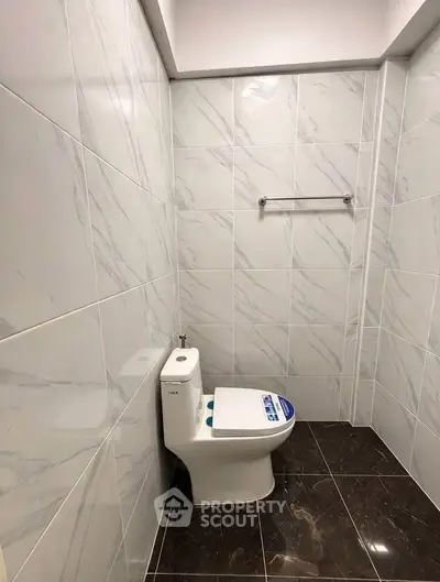 Modern bathroom with sleek marble tiles and contemporary toilet design.
