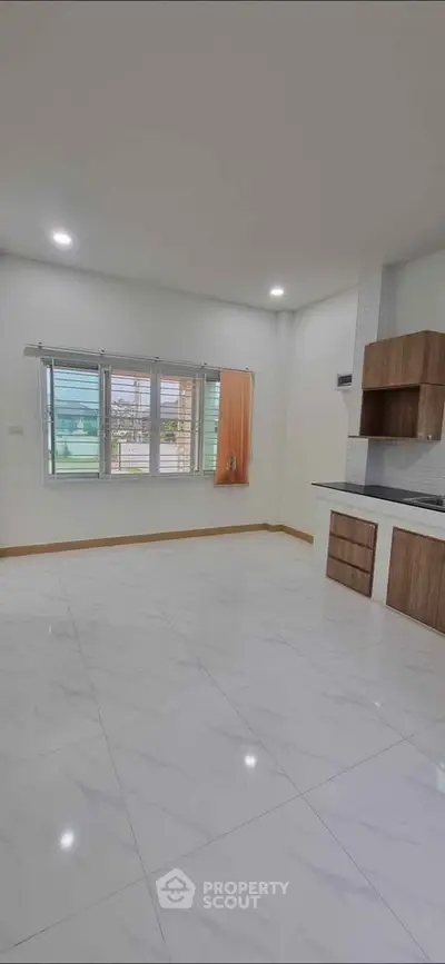 Spacious modern living room with large windows and sleek kitchen area