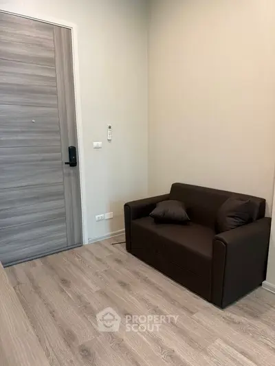 Cozy small living area with modern brown sofa and wooden flooring