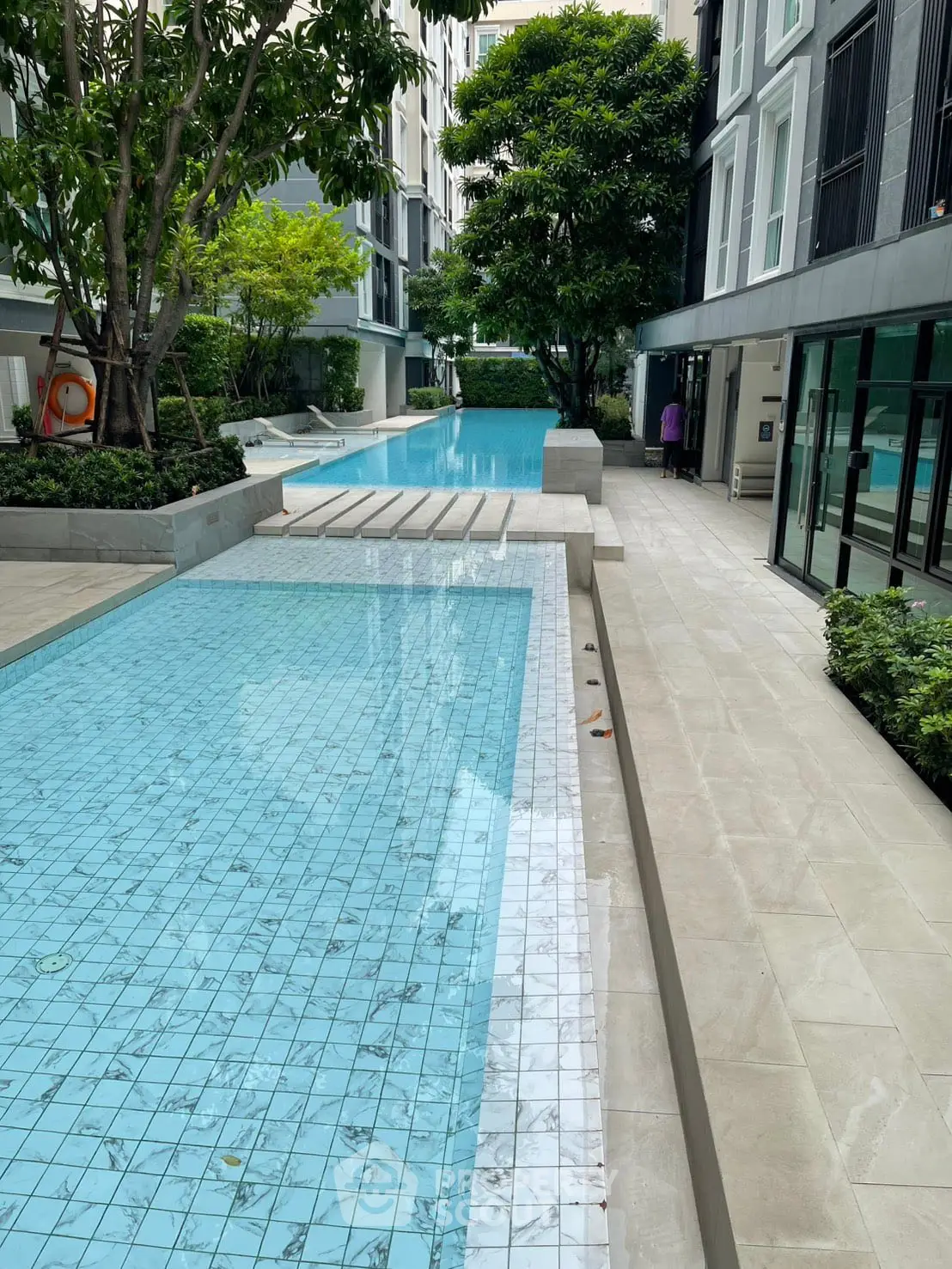 Luxurious apartment complex with stunning pool and lush greenery, perfect for relaxation and leisure.