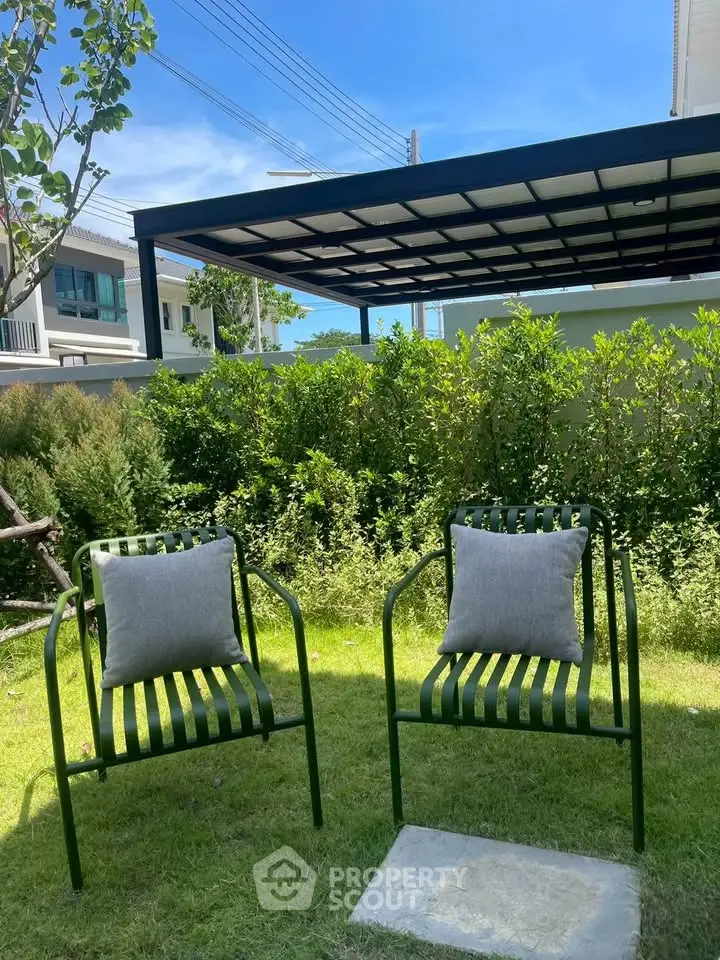 Charming garden area with modern chairs and lush greenery, perfect for relaxation.