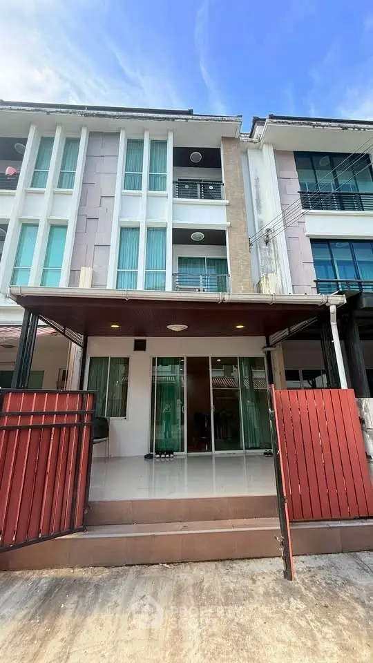 Modern townhouse exterior with red gate and large windows, perfect for urban living.