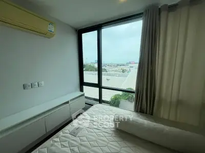 Modern bedroom with large window offering city view, featuring air conditioning and minimalist design.