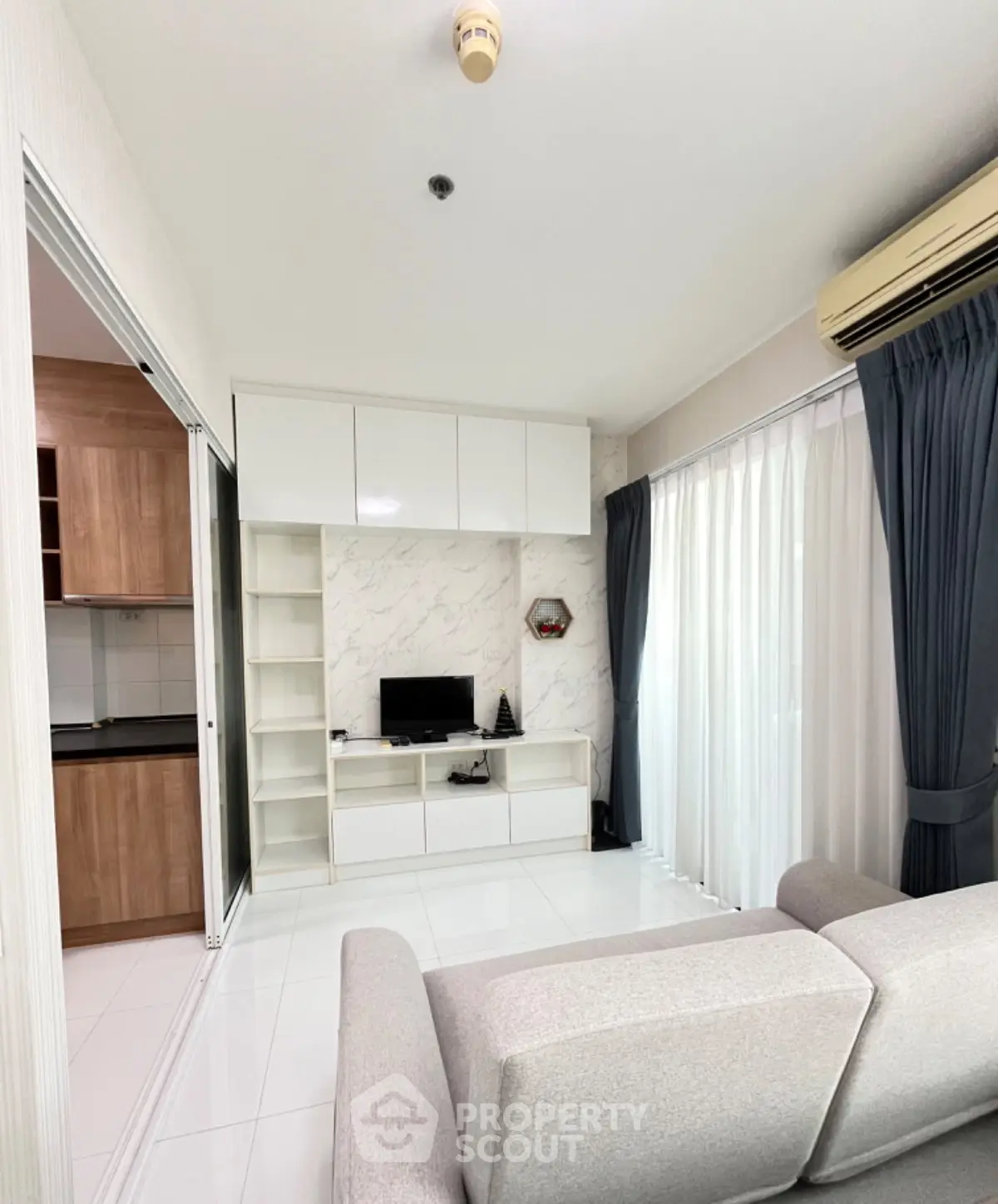 Modern living room with sleek design, featuring a cozy sofa, wall-mounted TV, and elegant curtains.