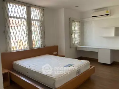 Spacious bedroom with natural light, featuring a modern bed and built-in desk, perfect for comfortable living.
