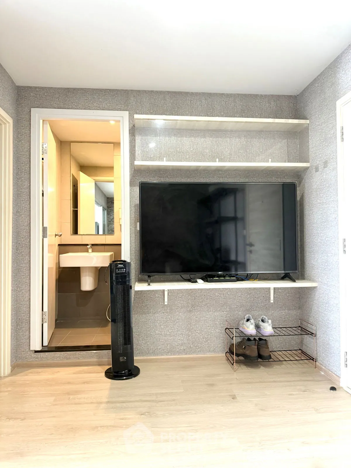 Modern living room with wall-mounted TV and open bathroom door, showcasing sleek design.