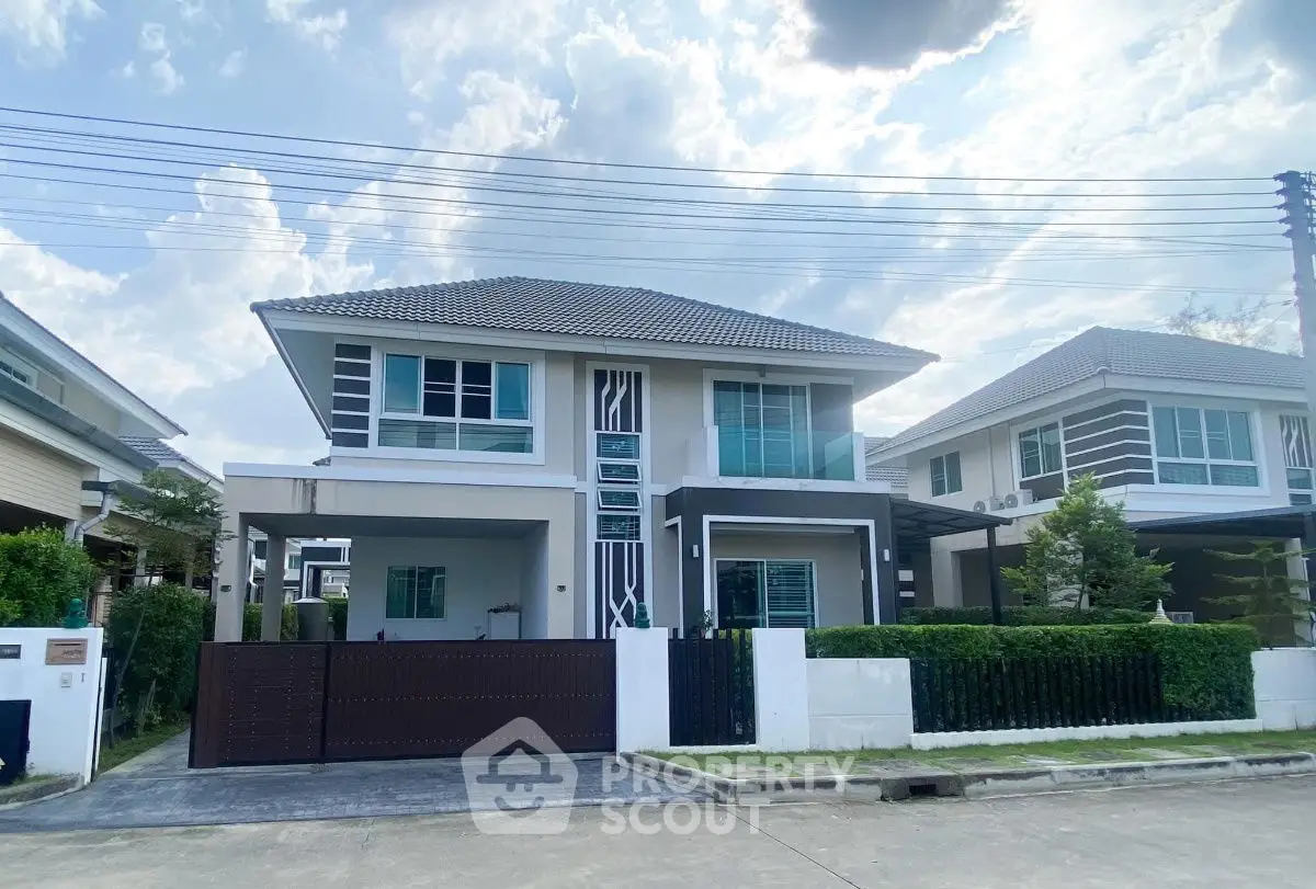 Modern two-story house with sleek design and spacious driveway in a suburban neighborhood.