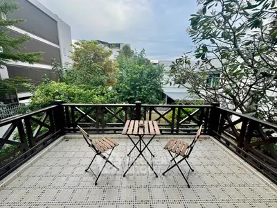 Charming balcony with wooden furniture and lush greenery view, perfect for relaxation.