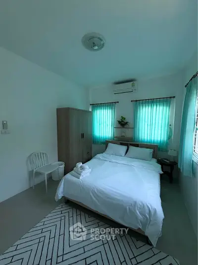 Cozy bedroom with natural light, featuring a comfortable bed, wardrobe, and air conditioning.