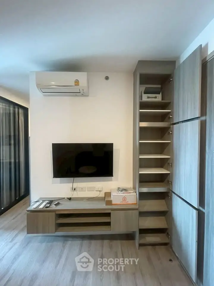 Modern living room with wall-mounted TV and sleek storage solutions in a stylish apartment.
