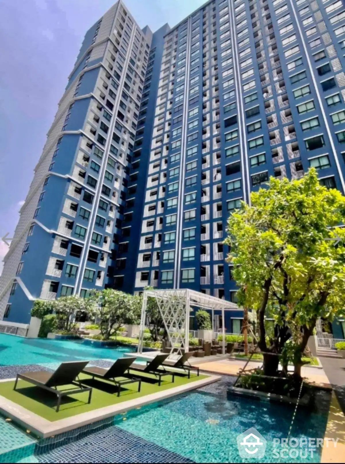 Luxurious high-rise condominium with poolside relaxation area and lush greenery.