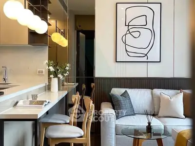Modern living room with stylish decor and open kitchen layout, featuring elegant lighting and contemporary artwork.