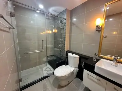 Modern bathroom with glass shower, sleek tiles, and elegant lighting