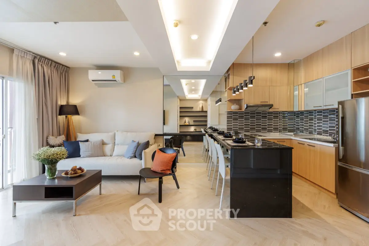 Modern open-layout living room and kitchen with stylish decor and natural light.