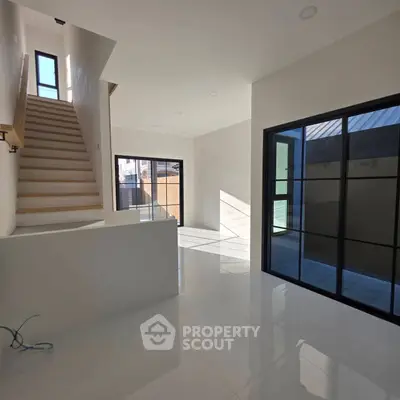 Modern interior with sleek staircase and large windows offering abundant natural light.