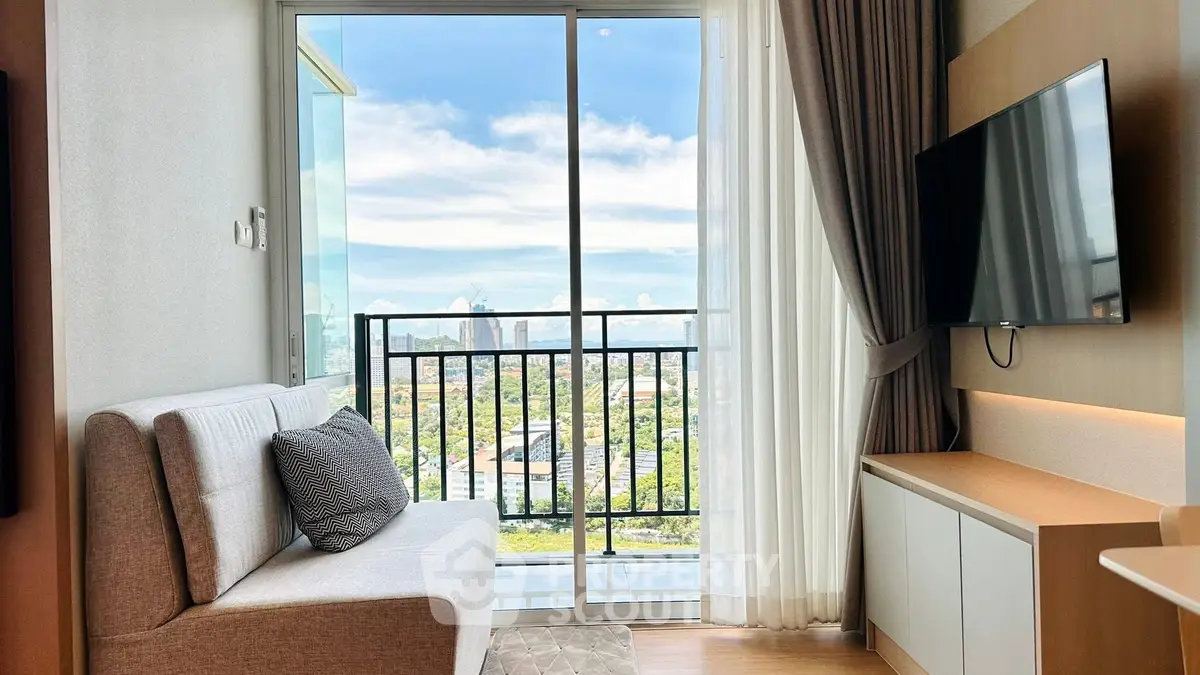 Modern living room with balcony and city view, featuring sleek TV setup and cozy sofa.