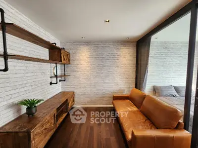 Chic urban living room with white brick walls and rich wooden floors, complemented by a stylish caramel leather sofa.
