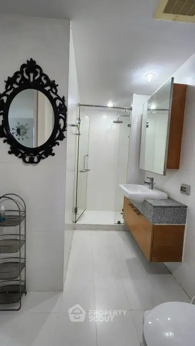 Modern bathroom with glass shower and stylish mirror in sleek design.