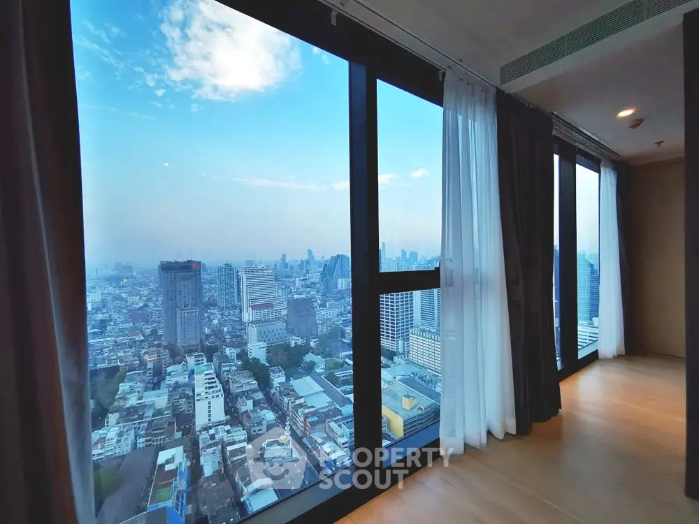 Stunning cityscape view from a high-rise apartment with floor-to-ceiling windows and elegant curtains.