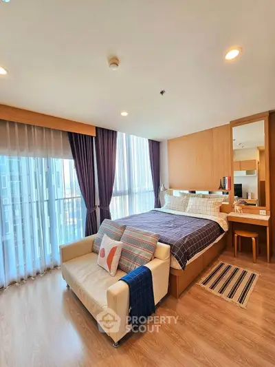 Spacious modern bedroom with large windows and cozy seating area in a stylish apartment.