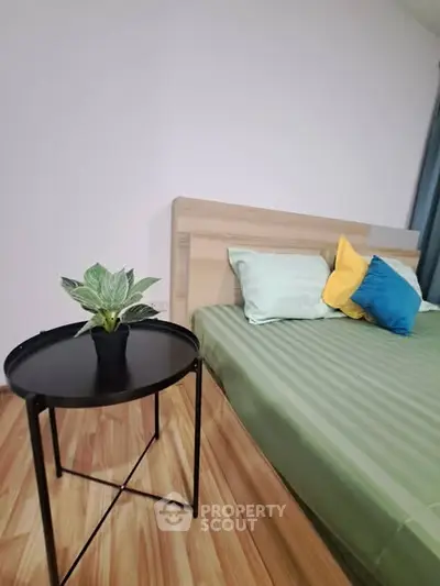 Modern bedroom with stylish decor and cozy atmosphere, featuring a sleek side table and vibrant pillows.