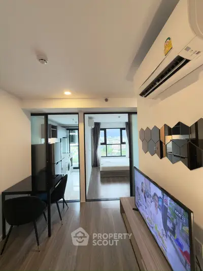 Modern apartment interior with open layout, featuring a cozy living area and a view of the bedroom.