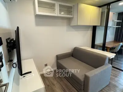 Modern living room with sleek gray sofa and wall-mounted TV in stylish apartment.